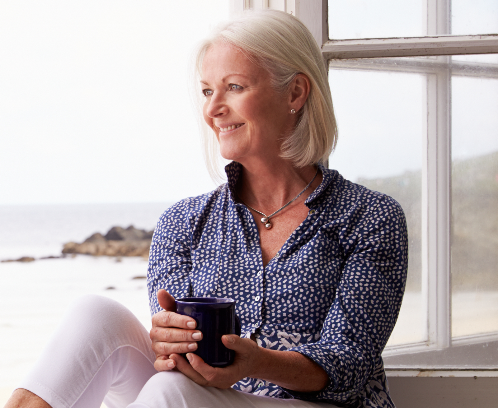 Woman-Sitting-At-Window-And-Looking-At-Beautiful-Beach-View